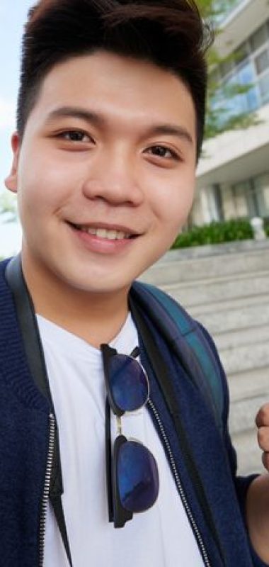 Smiling Vietnamese traveler taking selfie in foreign city